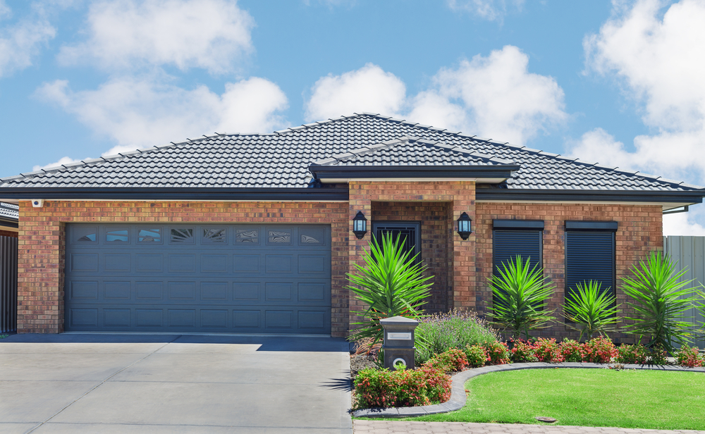 New,Brick,House,With,Green,Lawn,And,Plants